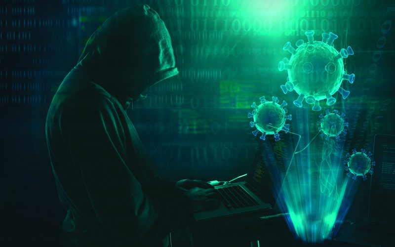 A hooded figure at a computer